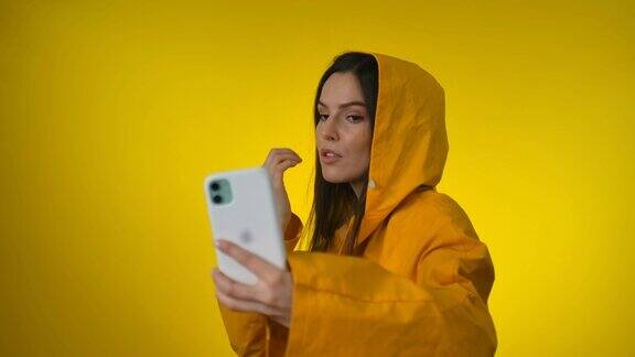 一名身穿亮黄色雨衣的年轻美女在摄影棚里自拍