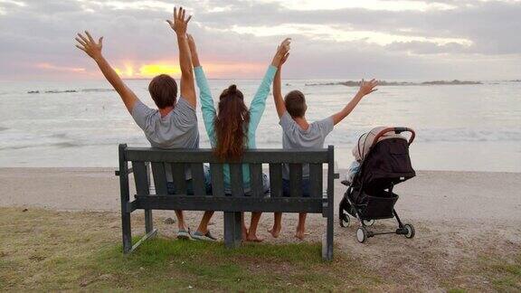 幸福的一家人坐在海边一起看日落
