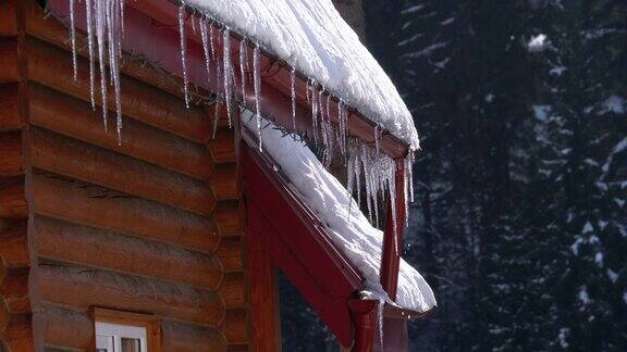 挂在木屋屋顶上的冰柱在阳光下融化滴落慢动作