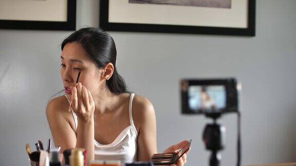 亚洲年轻女子在Youtube上录制视频在家里化妆直播病毒