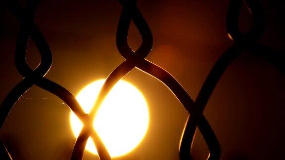 太阳在日落时在铁丝篱笆中经过时间流逝