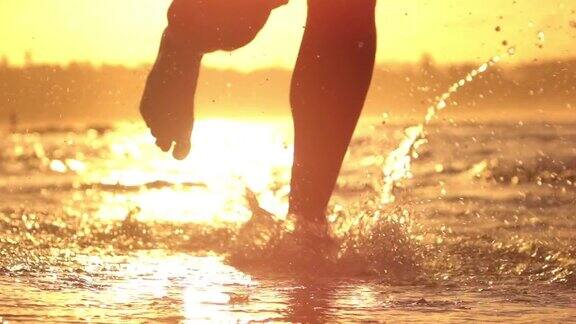 慢镜头特写镜头光晕活跃男子在海滩上慢跑溅起海水