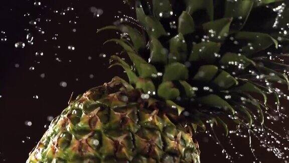 超级慢动作水滴在旋转的菠萝上在黑色背景上