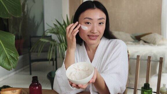 美丽的亚洲妇女准备自制面霜与天然成分的皮肤护理