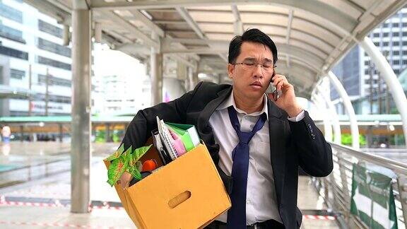 不高兴的商人与移动电话和携带他的财产在一个纸盒后被解雇
