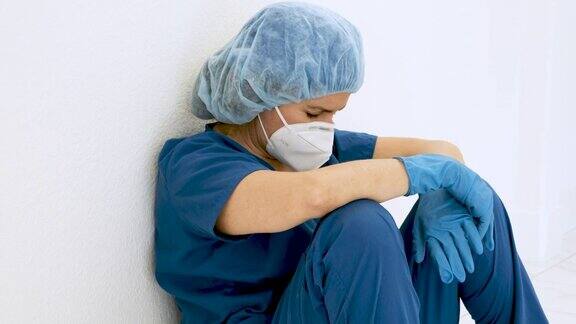 过度劳累、悲伤、疲惫的女医护人员坐在医院走廊的地板上