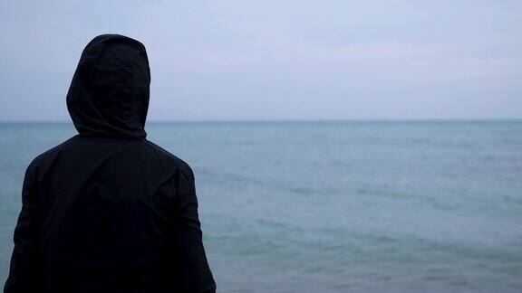 十几岁的男孩穿着连帽衫雨后站在海边看风景