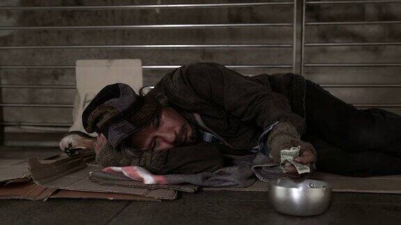 可怜的无家可归者或难民睡在城市街道的地板上社会纪录片