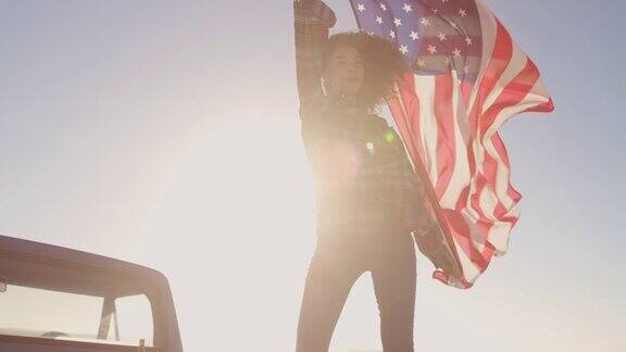 站在一辆4k皮卡上挥舞着美国国旗的女人