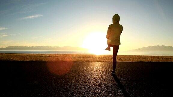 年轻的健身女子跑步在日出的海滨小径
