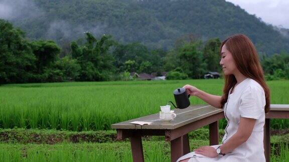 一名年轻女子在稻田里煮咖啡旁边是美丽的自然景色