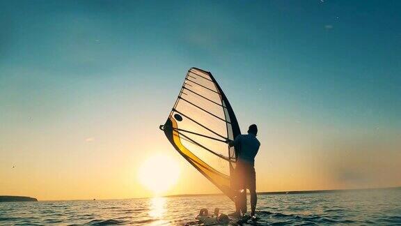 夕阳西下时一个男人在海边玩帆板