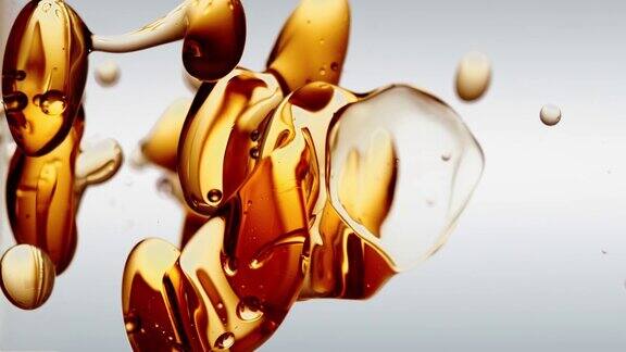 透明的化妆品橙色金色的油泡泡和形状在白色的背景