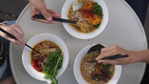俯视图的朋友享受三拉面汤在白色的盘子在圆桌健康东方饮食理念