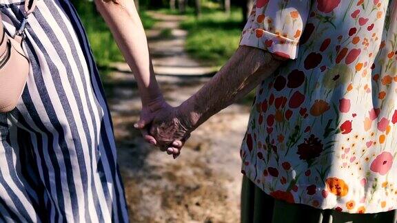 祖母和孙女手牵着手在公园里散步