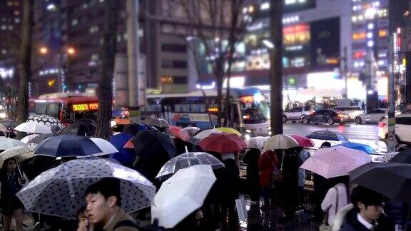 在韩国江南街上一群人撑着伞在雨中行走