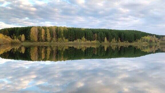 秋日五彩缤纷的枝叶倒映在平静的池塘水中
