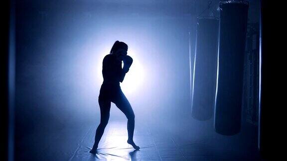 女运动员拳击在冒烟的演播室黑暗背景上的剪影