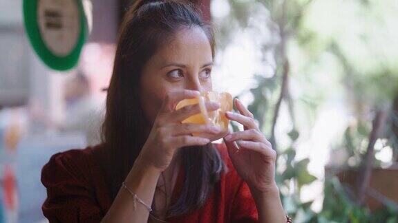 在咖啡馆里一位美丽的女子一边喝着热饮一边透过窗户向外看