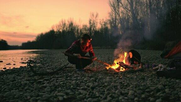 在斯洛文尼亚穆尔河的秋天河边女士给篝火添柴