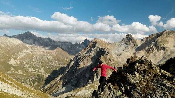 一个年轻人爬上高山上的岩石脊