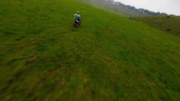 空中跟随动态视图耐力摩托车骑手速度驾驶在绿色的草地