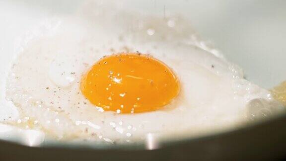 在白锅里煎鸡蛋加入胡椒