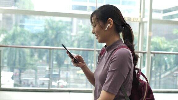 一名亚洲女性在城市中使用智能手机进行社交媒体