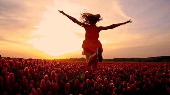 快乐的女孩在夕阳花丛中跳跃