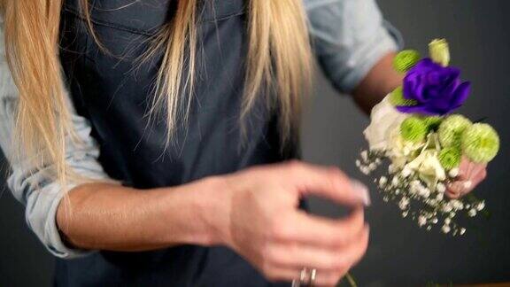 慢动作拍摄的专业金发女花艺师的手安排美丽的花束在花店花艺手工和小的商业概念