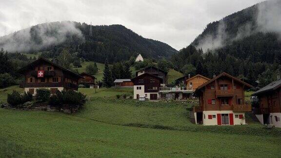 瑞士瓦莱州典型的瑞士村庄在阴天雨天草木山谷的小屋瑞士国旗