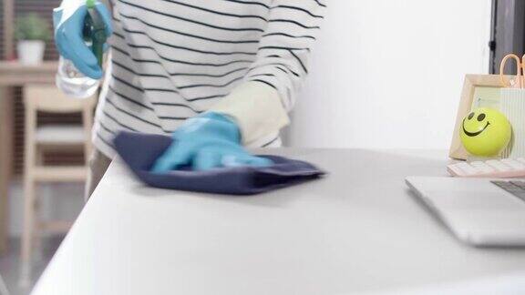 一名妇女用抗菌消毒擦拭巾清洁办公桌以杀灭冠状病毒