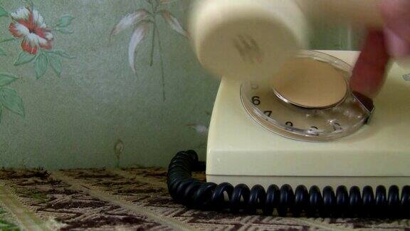 一个女人在用手拨通一个旧的白色电话