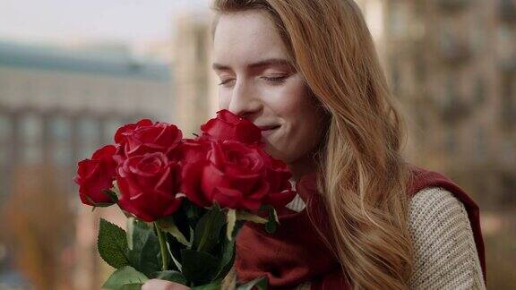 女人双手捧玫瑰放在脸上快乐的女孩在户外闻着花香
