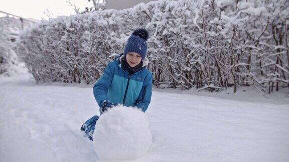 小男孩在冬天的一天堆雪人