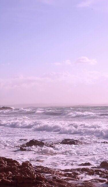 在阳光明媚、波涛汹涌的海面上巨浪和水花拍打着岩石垂直视频巨大的海浪在希腊希俄斯的MegasLimnionas海滩上冲破岩石
