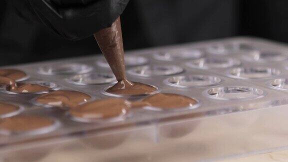 用烹饪袋将巧克力或巧克力奶油倒入模具中特写镜头巧克力制造商手工制作有机巧克力