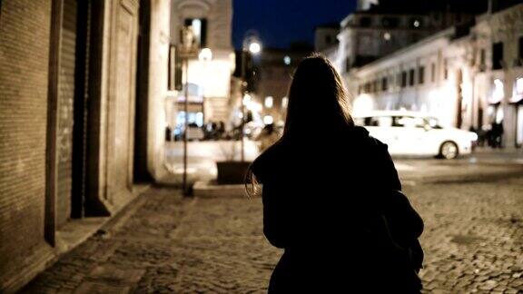 背影年轻时尚的女人走过冷清的小巷深夜主要街道城市道路