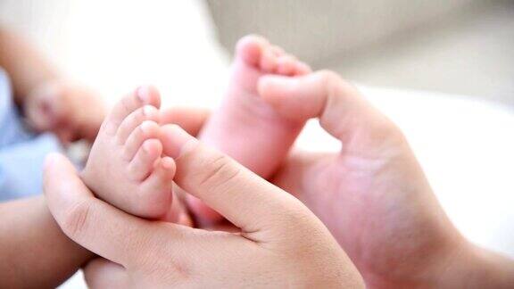 母亲双手抱着新生儿的脚动作缓慢