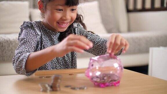 小女孩很高兴把一枚硬币放进存钱罐里存钱