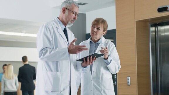 在医院医生在使用平板电脑时进行讨论背景:患者与医务人员新型现代化、功能齐全的医疗设施