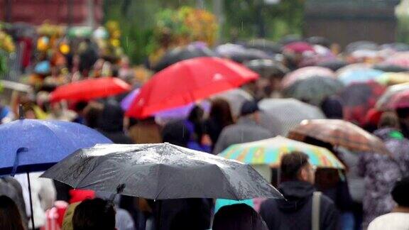 人们在繁忙的商业街撑着雨伞挡雨真正的时间红色的伞人们在雨中带着雨伞上下班模糊的散景雨天的城市街道的自然背景