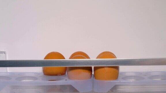 手的特写轻轻地把鸡蛋放在冰箱里