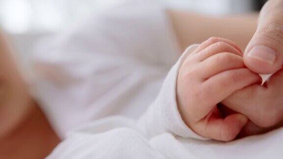新生儿抱着妈妈的手指在家睡觉人寿保险关怀保护
