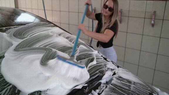 一名年轻女子在自助洗车处擦洗她的汽车挡风玻璃