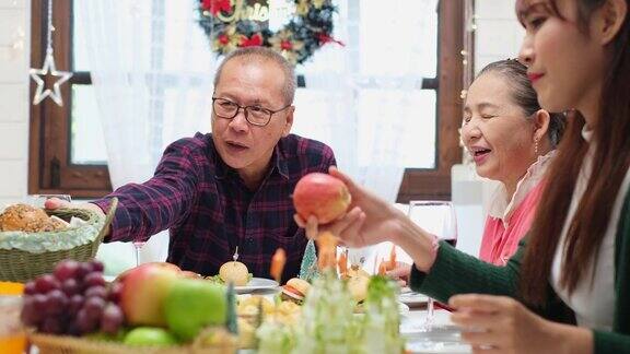 感恩节或圣诞节庆祝亚洲家庭晚餐概念阖家欢乐共进节日晚餐爸爸妈妈和女儿在家里吃晚饭年迈的父母在庆祝