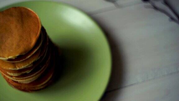 煎饼早餐厨房桌子上绿色盘子上的一堆甜煎饼