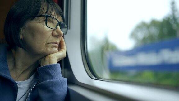 戴眼镜的老年妇女的特写肖像乘火车旅行望向窗外