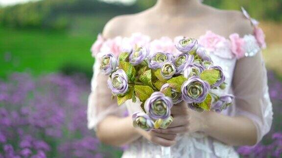 美丽的新娘手捧一束鲜花在山上的花园里