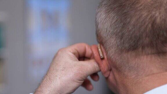 有听力丧失症状的老年人男人戴着助听器成熟紧张的男人手指靠近耳朵带助听器的人